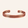 Jonc ouvert en cuivre rouge-orangé à fils torsadés en motif d'épi, pastilles rondes aux extrémités Jonc ouvert en cuivre rouge-orangé à fils torsadés en motif d'épi, pastilles rondes aux extrémités