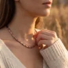 Collier en cuivre à maillons croisés en X, reflets rosés, porté au cou