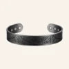 Bracelet jonc large de teinte noire, gravé de nœuds celtiques autour d'un arbre, pastilles rondes aux extrémités