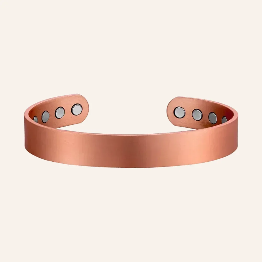 Jonc ouvert en cuivre rosé à surface lisse, avec quatre pastilles rondes claires à l'intérieur de chaque extrémité